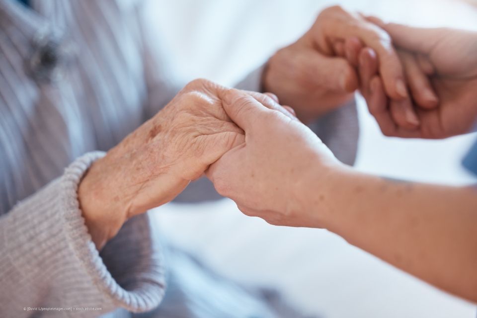 Pflegerin hält die Hände einer Seniorin