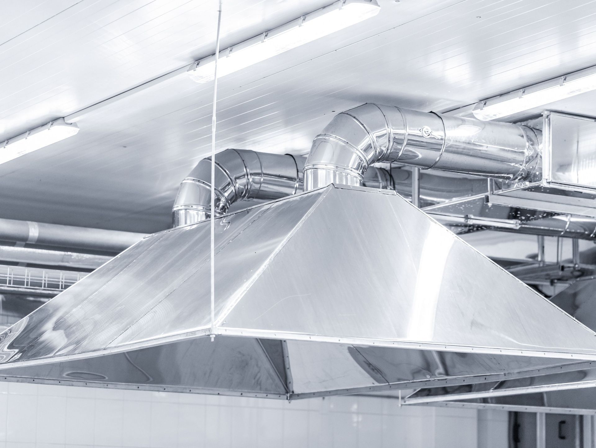 Una campana extractora de acero inoxidable cuelga del techo de una cocina.