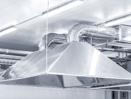 Una campana extractora de acero inoxidable cuelga del techo de una cocina.
