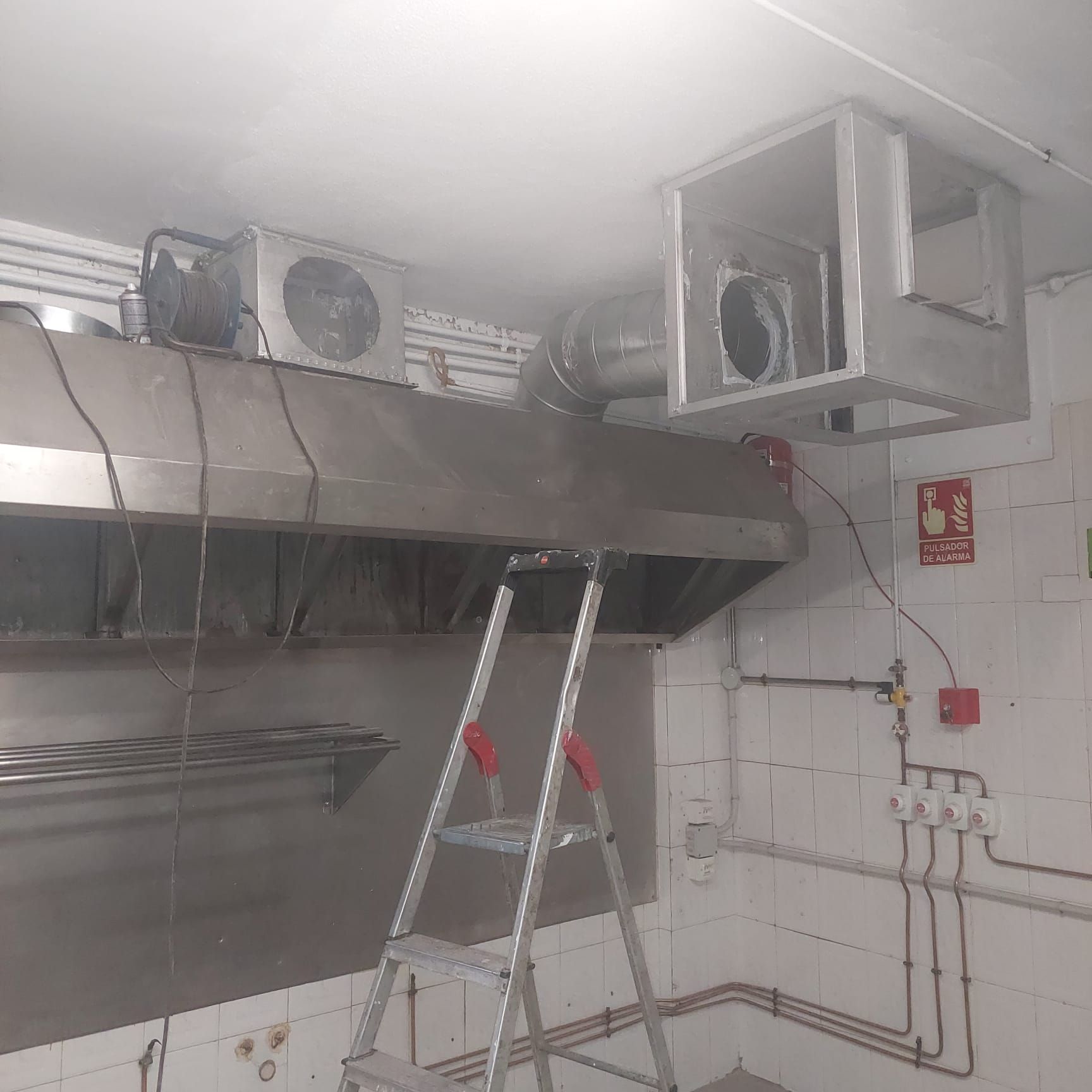 Una cocina con escalera y campana de acero inoxidable.