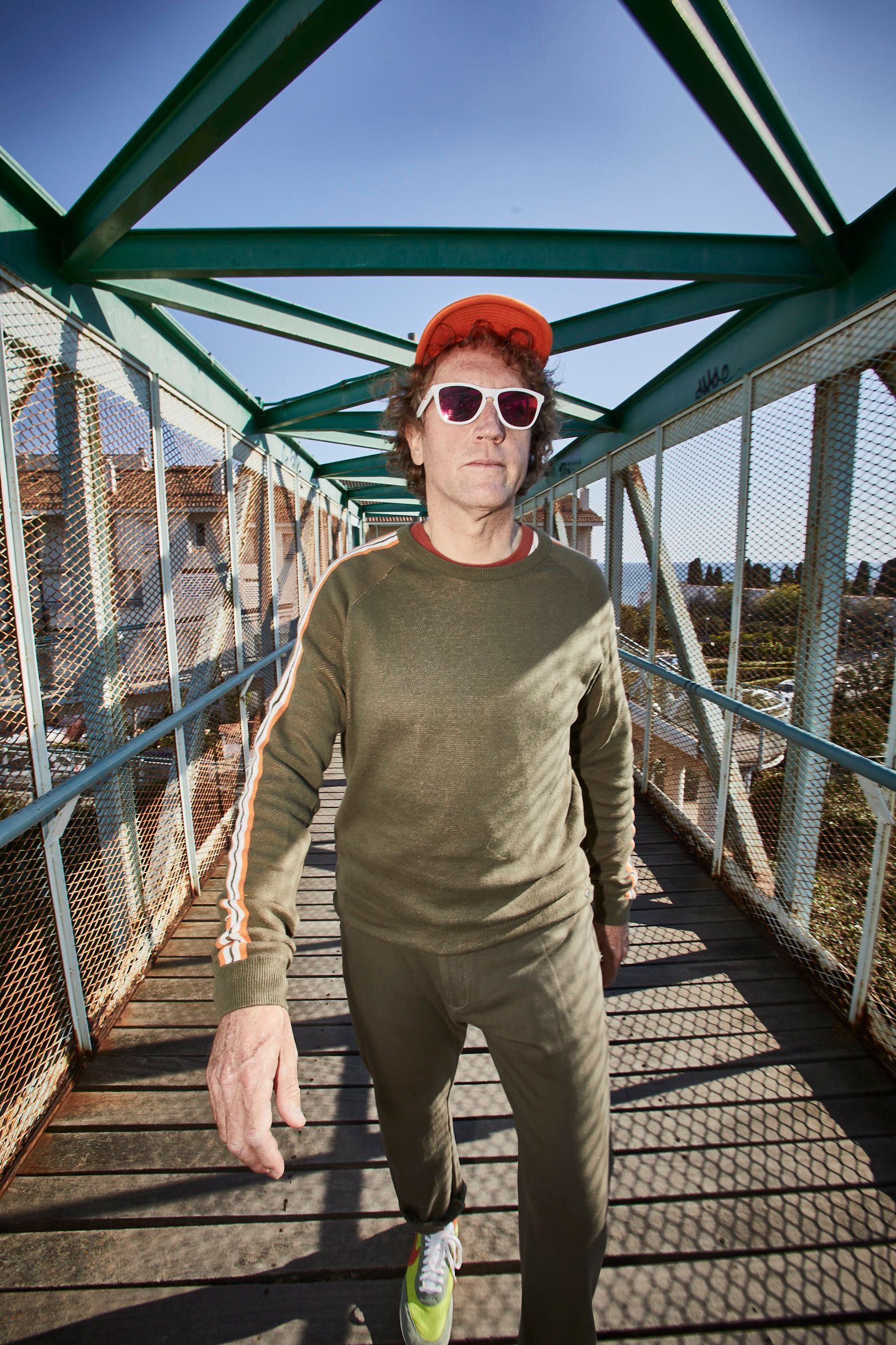 Un hombre que lleva gafas de sol y sombrero camina por un puente.