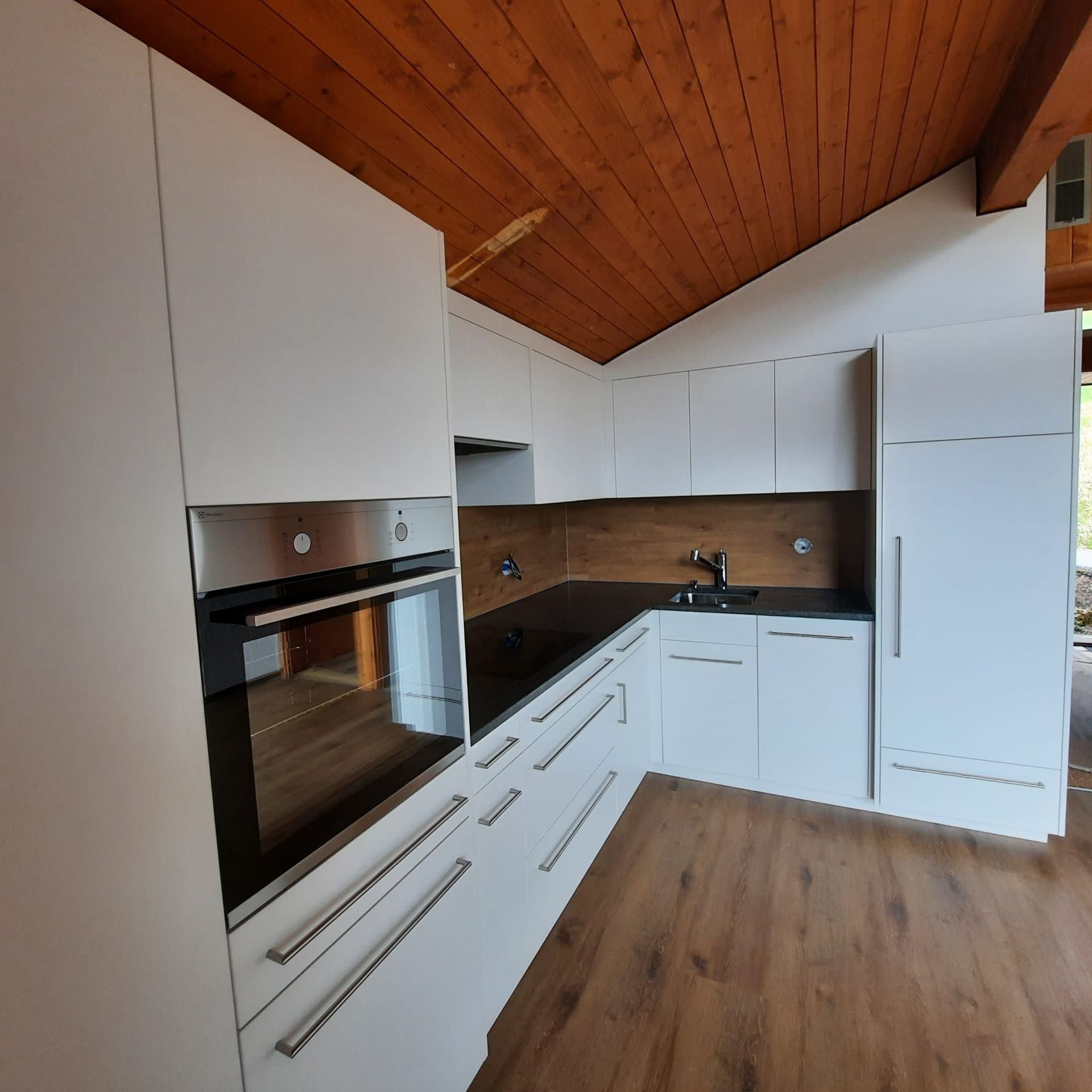 Cuisine blanche, plan de travail en granit noir, sol et entre-meuble identique!