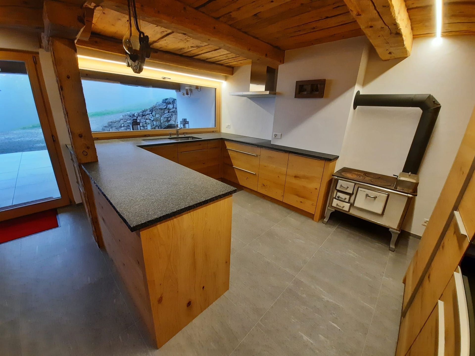 Cuisine neuve en chêne dans un chalet rénové rempli de charme - Plan de travail Impala, champs bruts - poignées inox