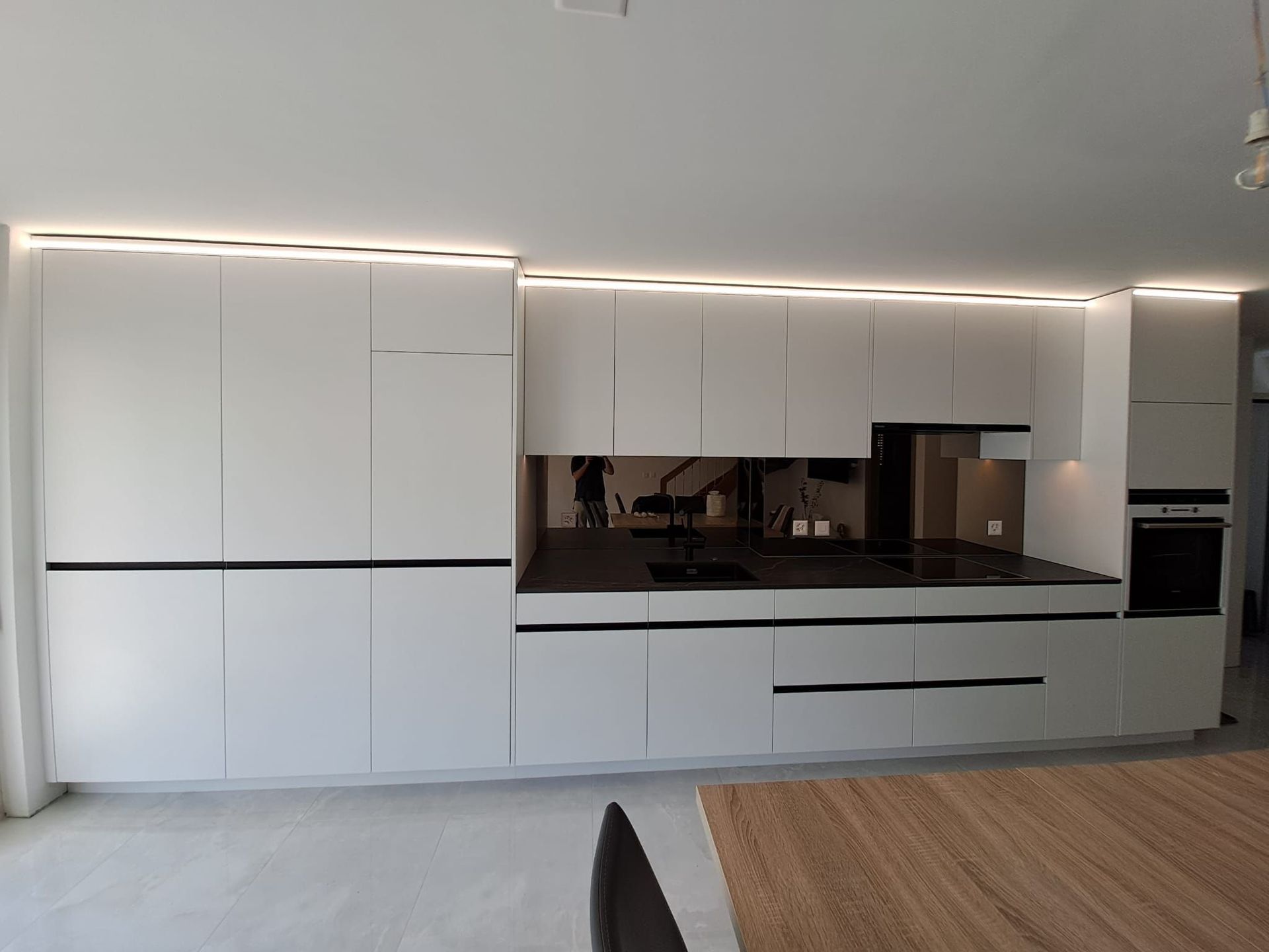 Cuisine en stratifié avec poignée profilée noir, crédence en miroir bronze, plan de travail dekton Laurent