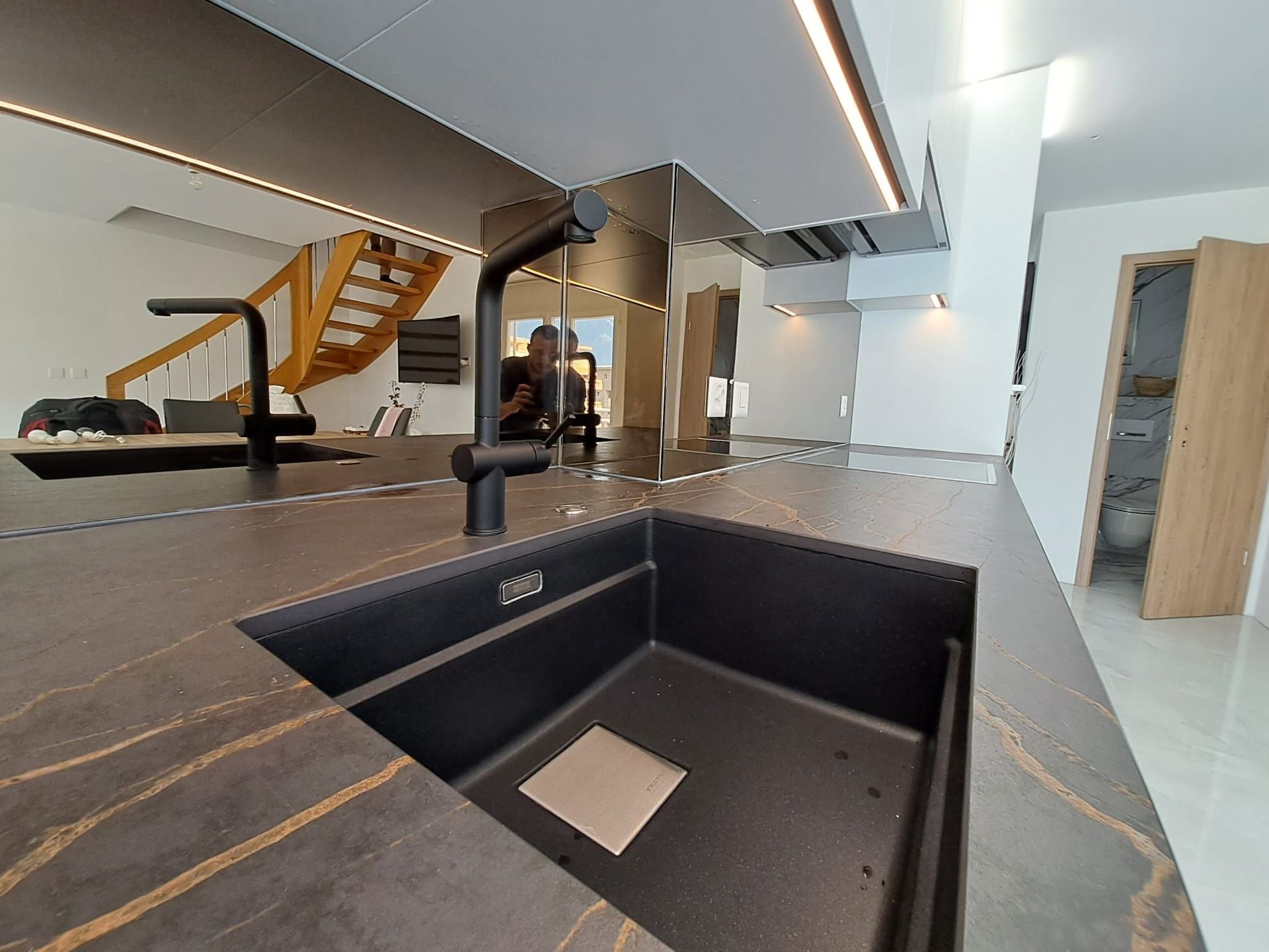 Cuisine en stratifié avec poignée profilée noir, crédence en miroir bronze, plan de travail dekton Laurent