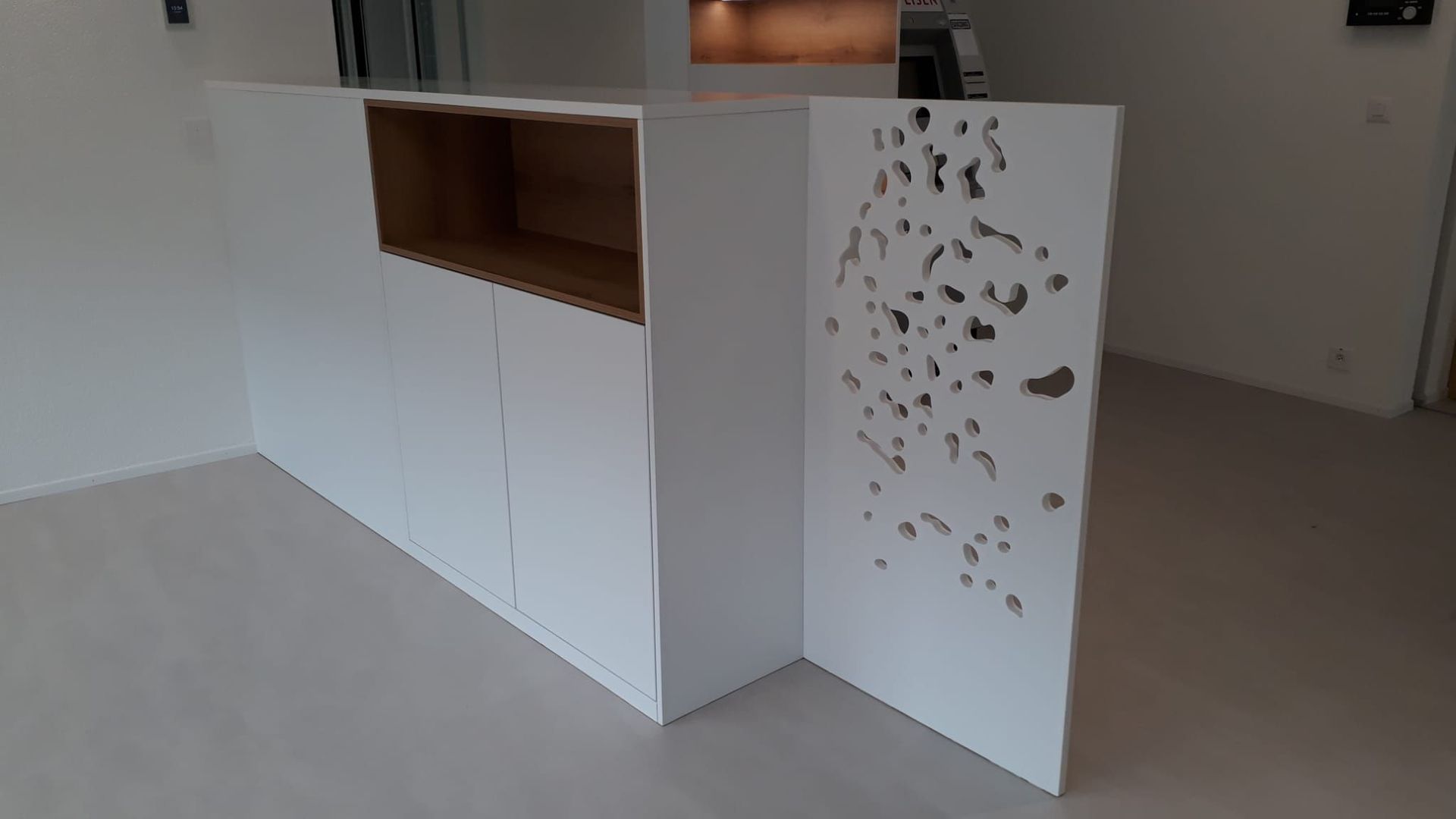 Raiffeisen Troistorrents: Meuble de séparation en stratifié blanc, avec panneau ajouré en corian