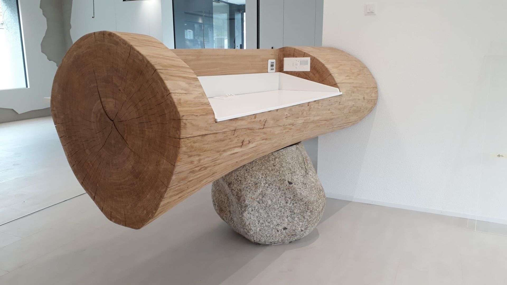 Raiffeisen Troistorrents: Guichet creusé dans une bille de chêne de et posé sur une pierre, vue à de l'arrière