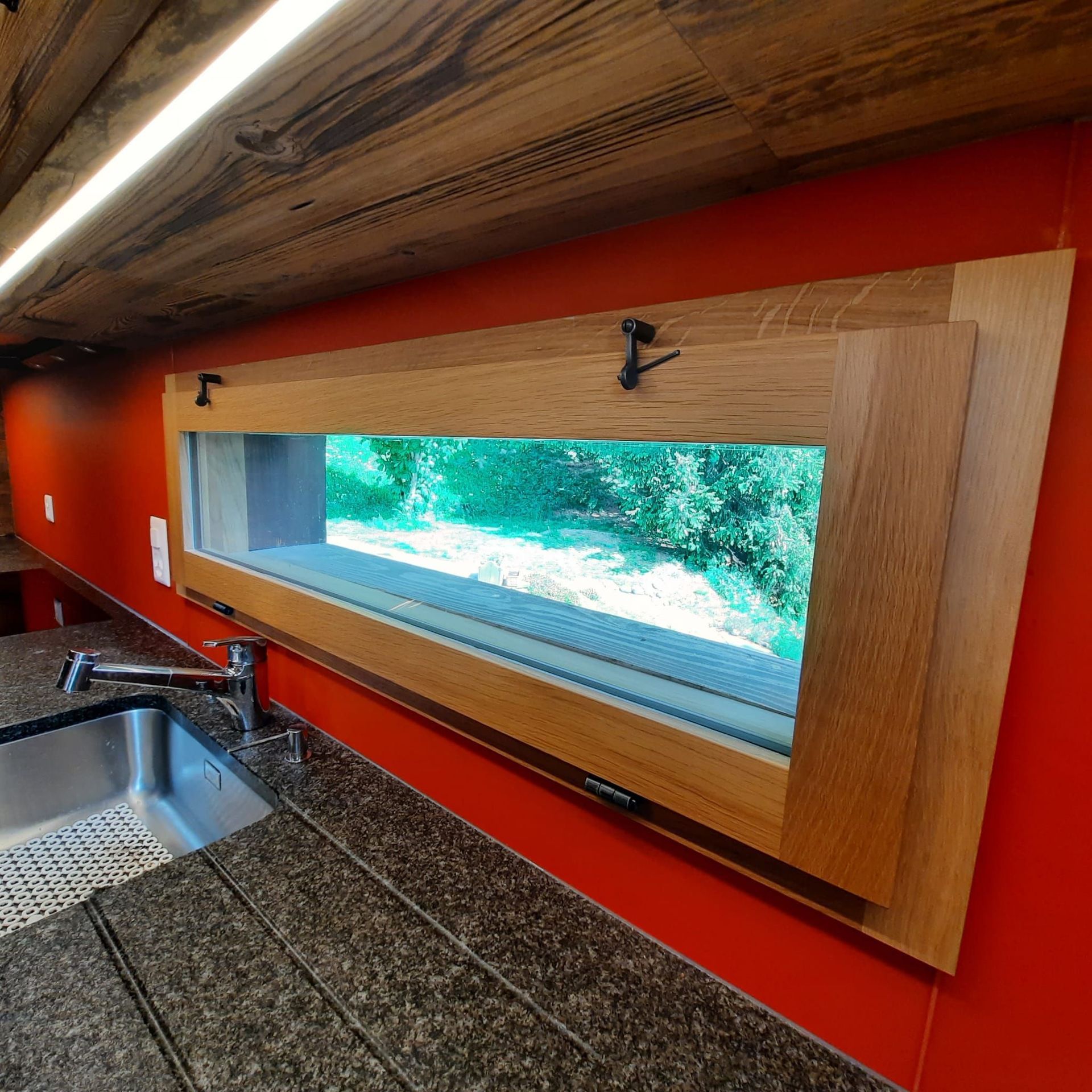 Cuisine vieux bois et chêne. Granit impala flammé brossé . Entre meuble en verre. Petite fenêtre sur mesure