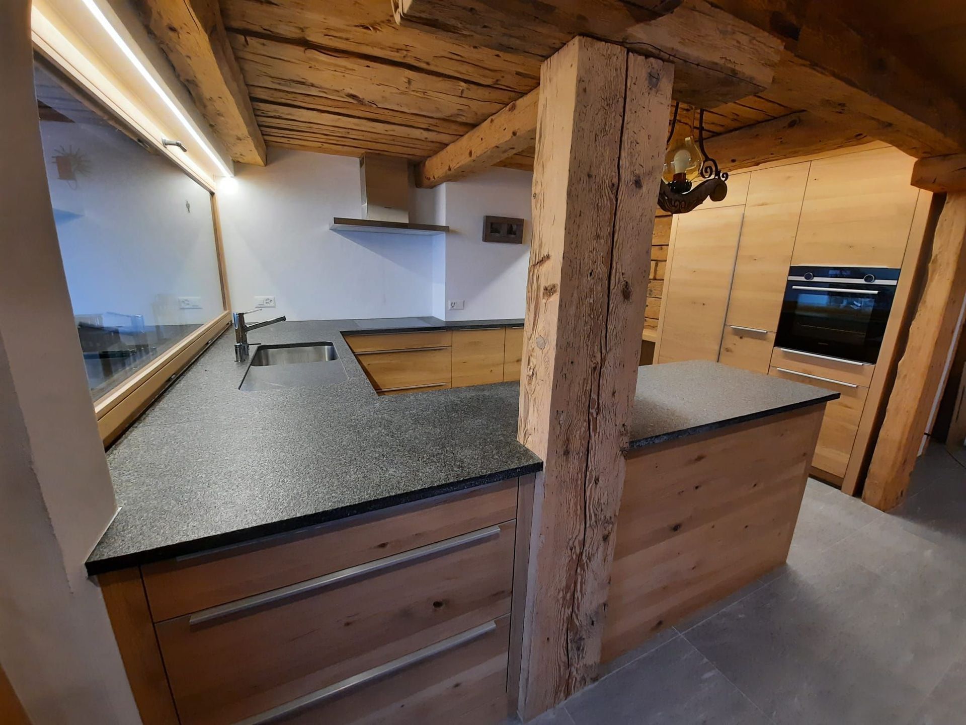 Cuisine neuve en chêne dans un chalet rénové rempli de charme - Plan de travail Impala, champs bruts - poignées inox