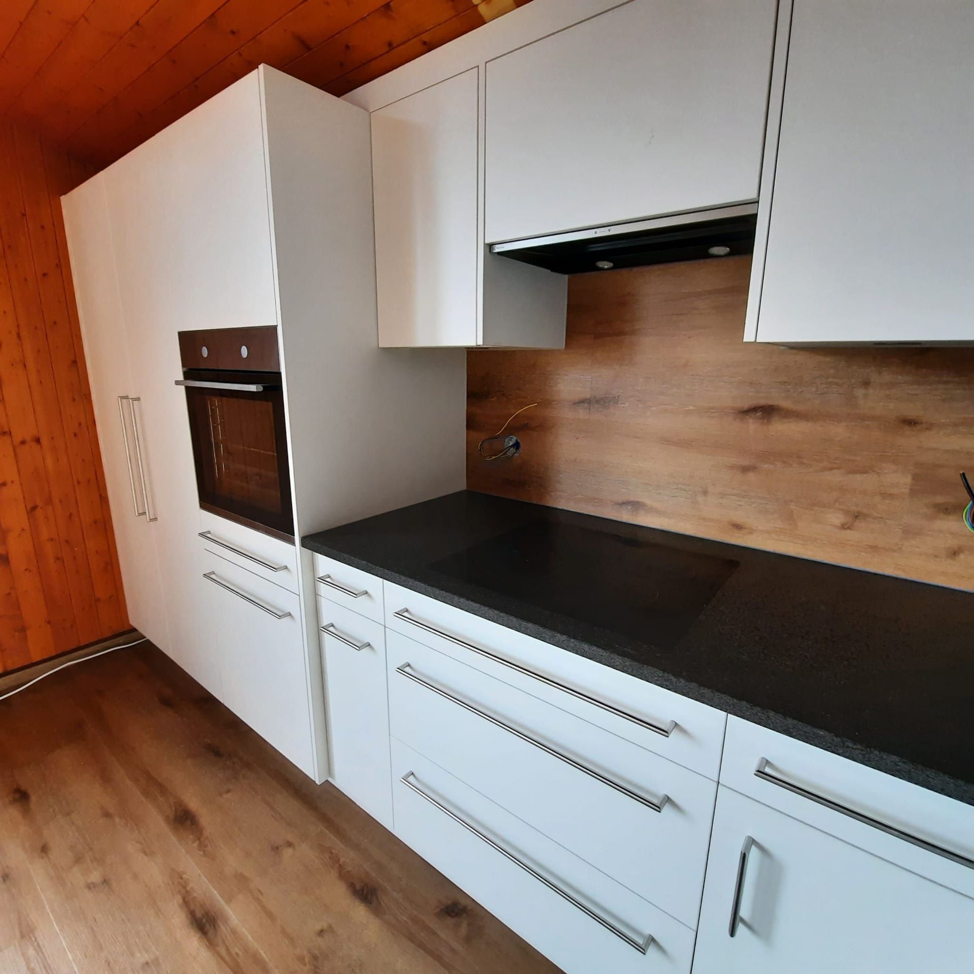 Cuisine blanche, plan de travail en granit noir, sol et entre-meuble identique!