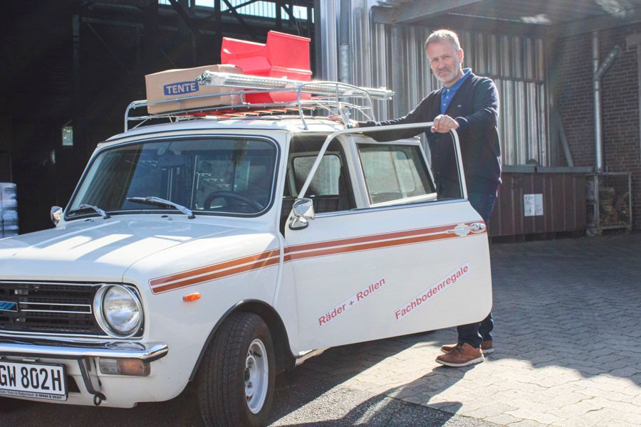 ein Mann steht neben einem kleinen weißen Auto