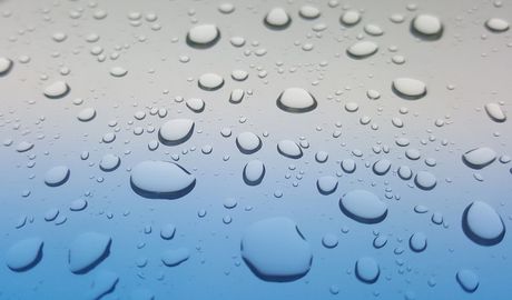 Gotas de agua sobre una superficie de color azul claro y gris.