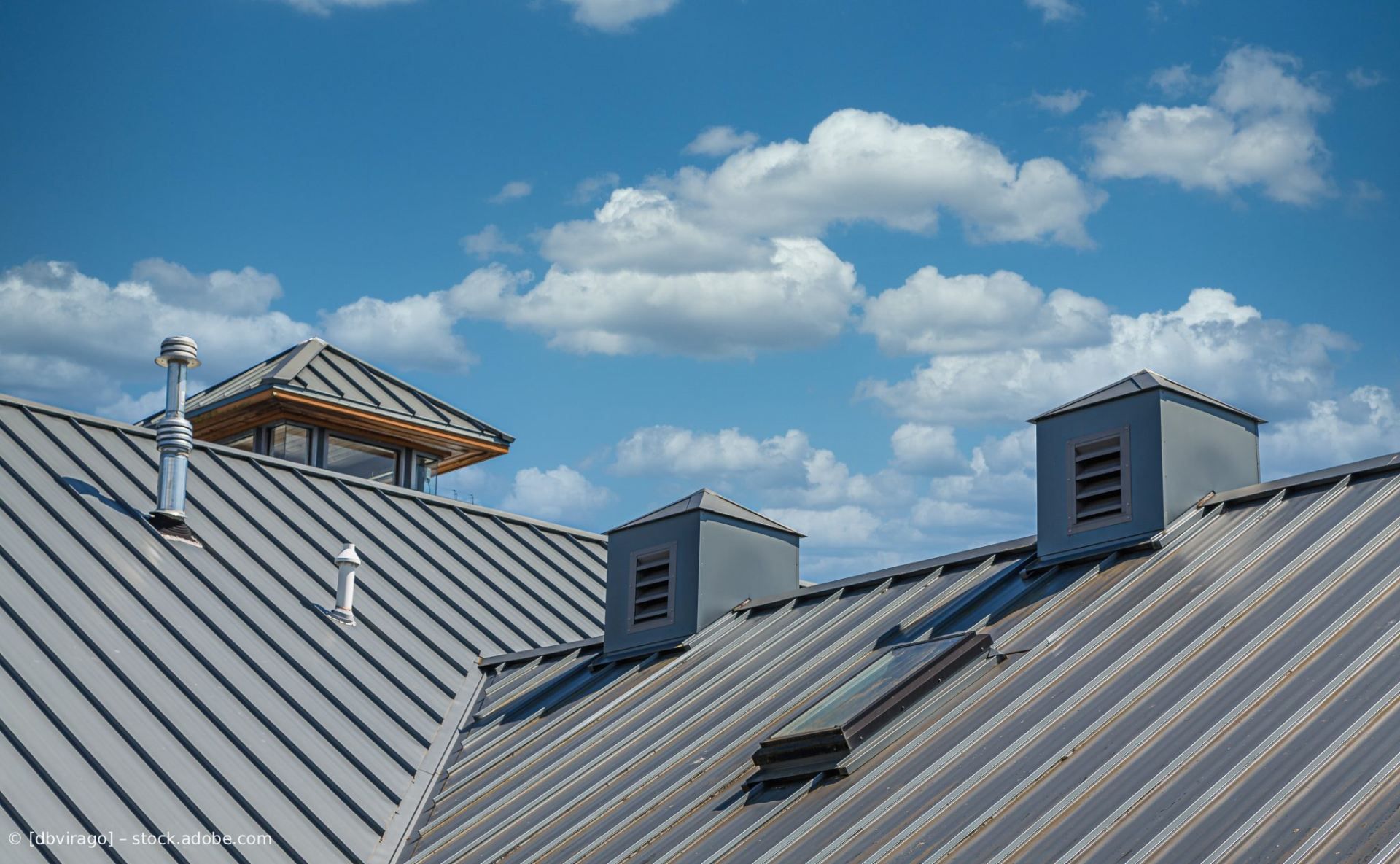 Metalldächer mit grauen Lüftungsöffnungen unter blauem Himmel mit vereinzelten Wolken