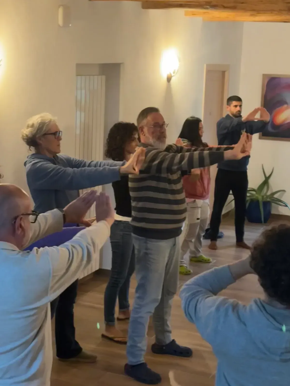 Adults in a bright room practicing a group exercise with arms extended forward