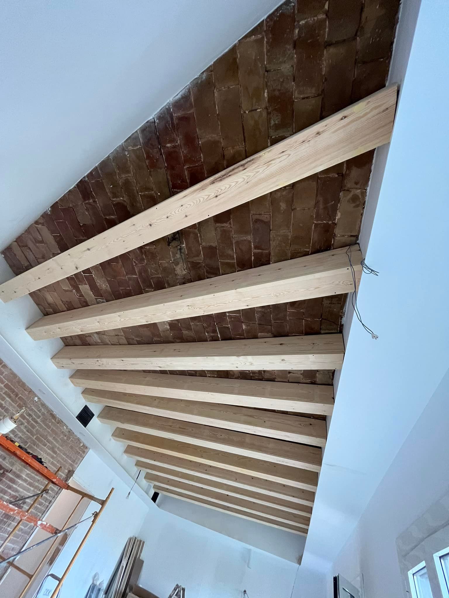 Vigas de madera que sostienen un techo de ladrillo en una habitación en construcción.