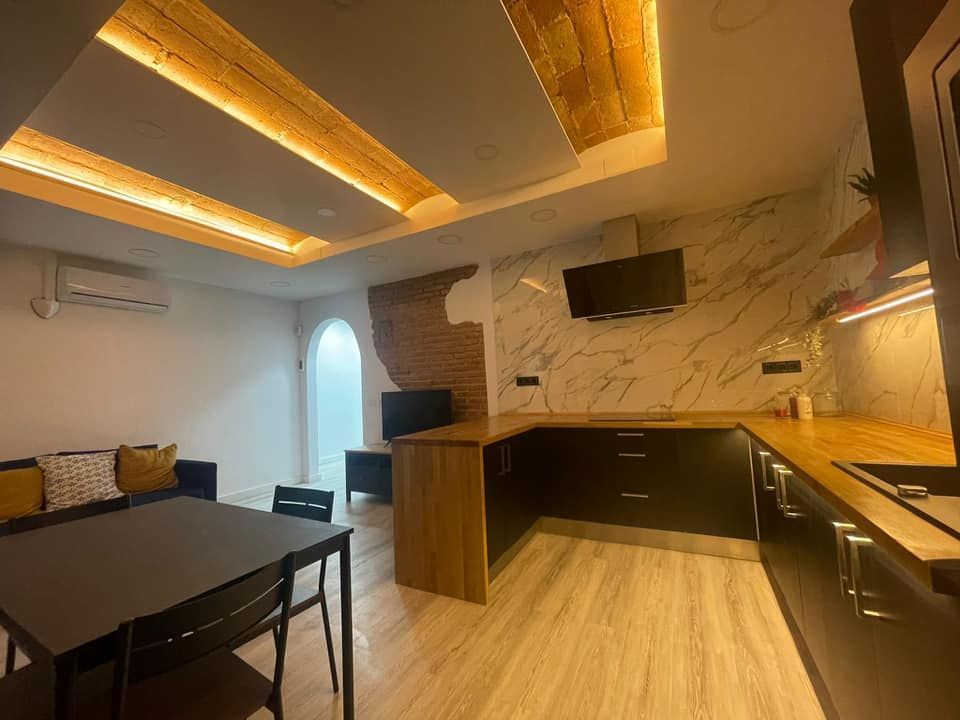 Cocina y comedor modernos con gabinetes oscuros, protector contra salpicaduras de mármol y ladrillos a la vista.