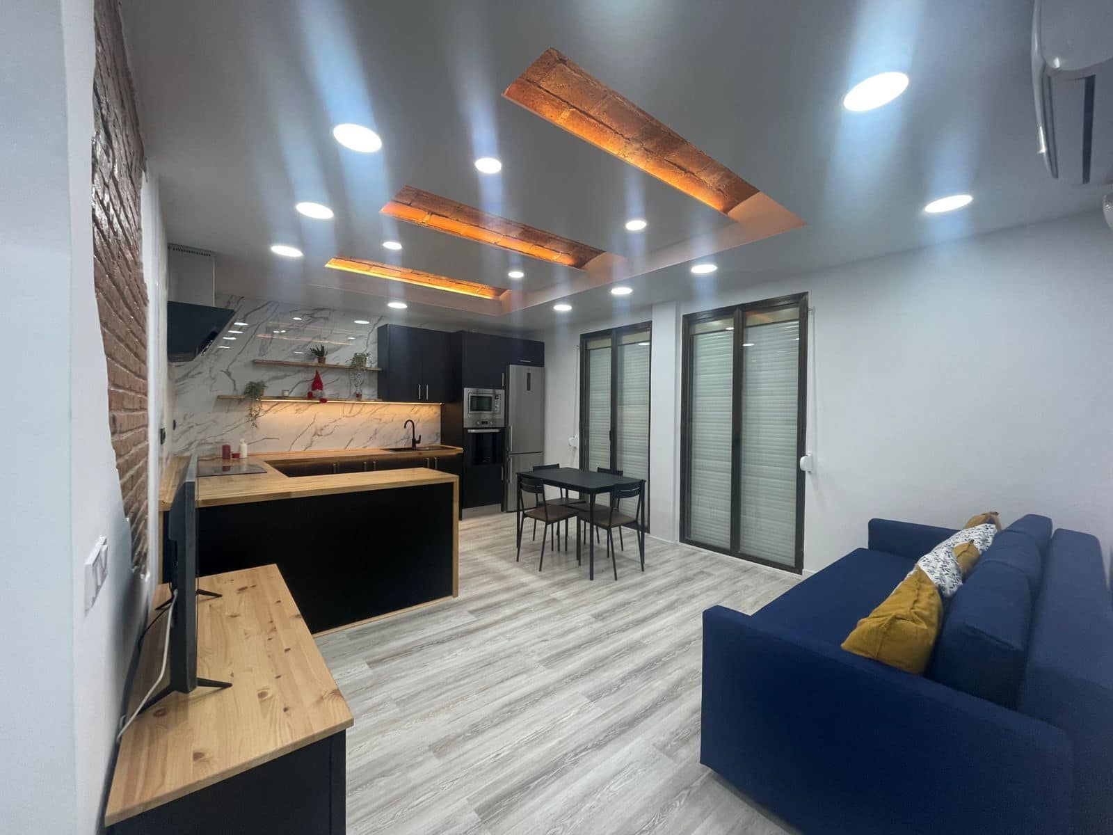 Interior de moderno apartamento tipo estudio con cocina, comedor y sofá.