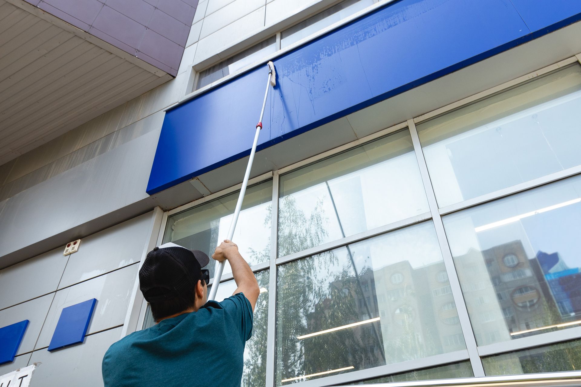 Eine Person wischt einen glänzenden, nassen Boden; daneben steht ein Reinigungswagen mit roten und blauen Eimern.