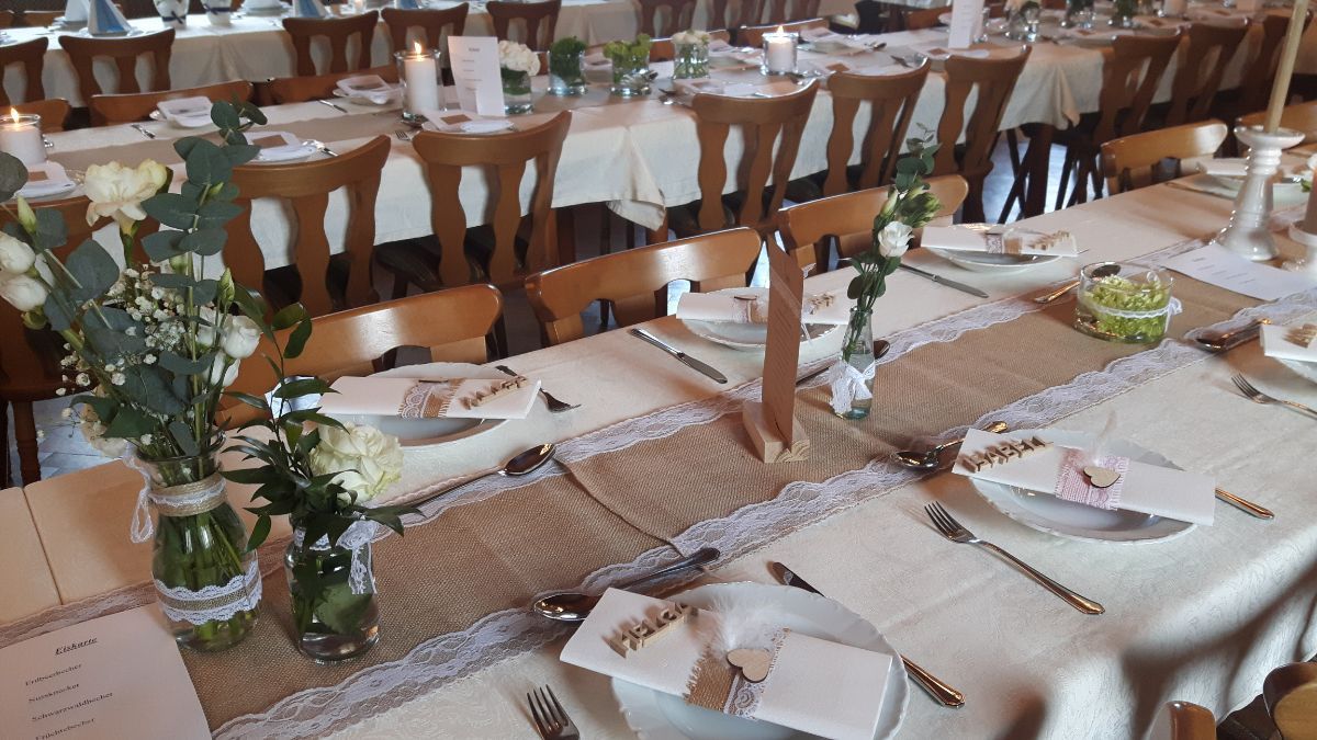 Tischdekoration für den Hochzeitsempfang mit Blumendekorationen, beiger Tischwäsche und Namenskarten.