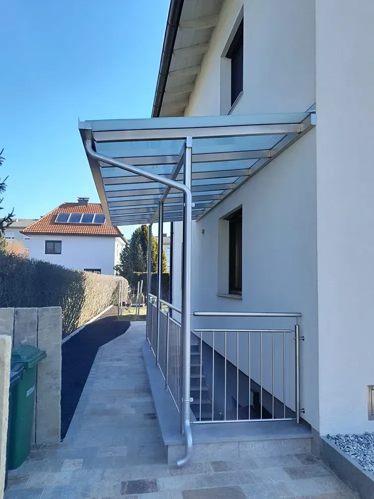 Ein weißes Haus mit einem Glasdach und einem Edelstahlgeländer