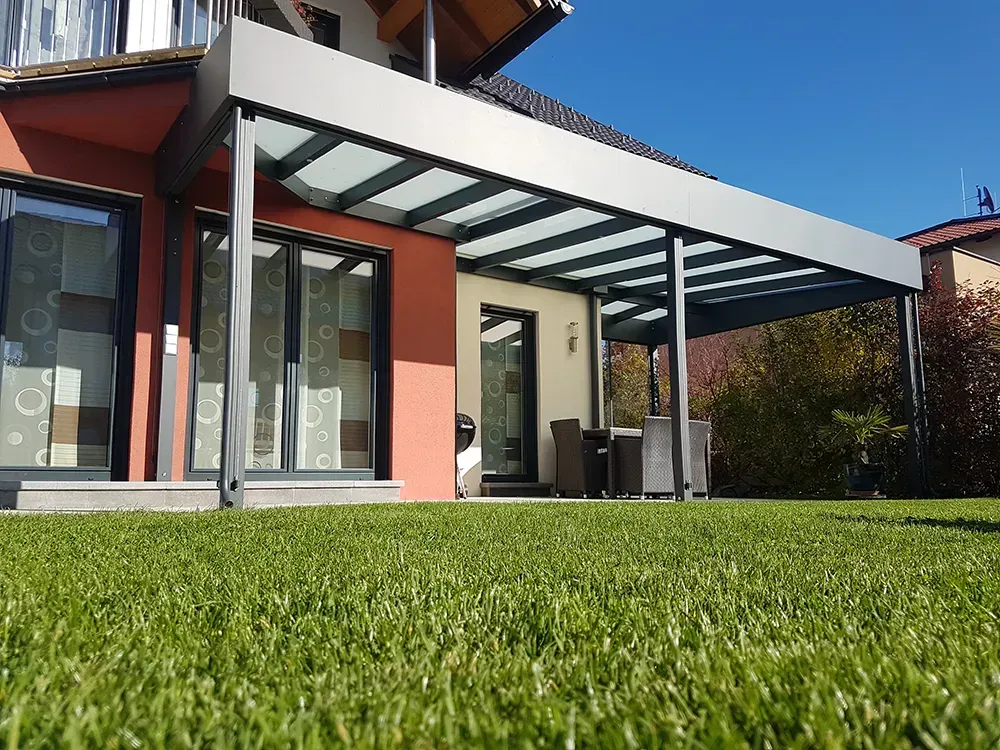 Ein Haus mit überdachter Veranda und einem üppigen grünen Rasen davor.