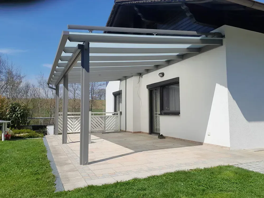 Ein weißes Haus mit einer Glaspergola an der Seite.