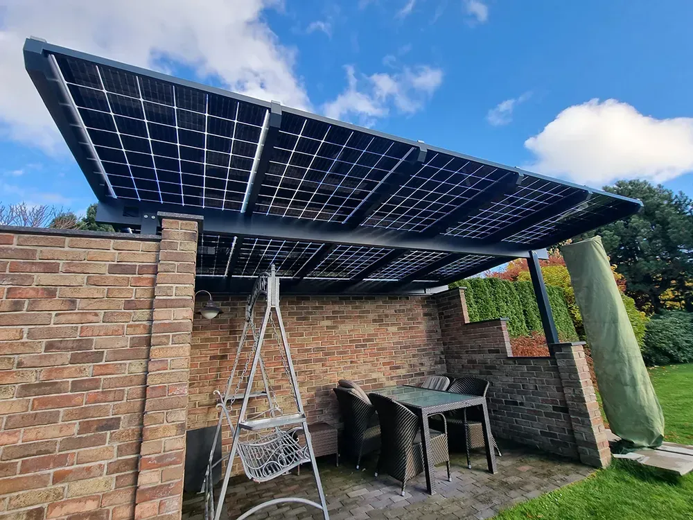 Eine Terrasse mit Tisch und Stühlen unter einem Baldachin mit Sonnenkollektoren.