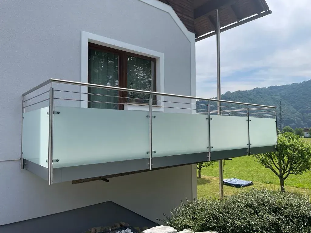 Ein Balkon mit einem Edelstahlgeländer an der Seite eines Hauses