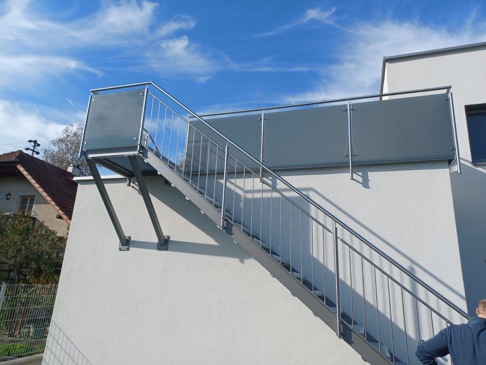 Ein Mann steht neben einer Treppe an der Seite eines Gebäudes.