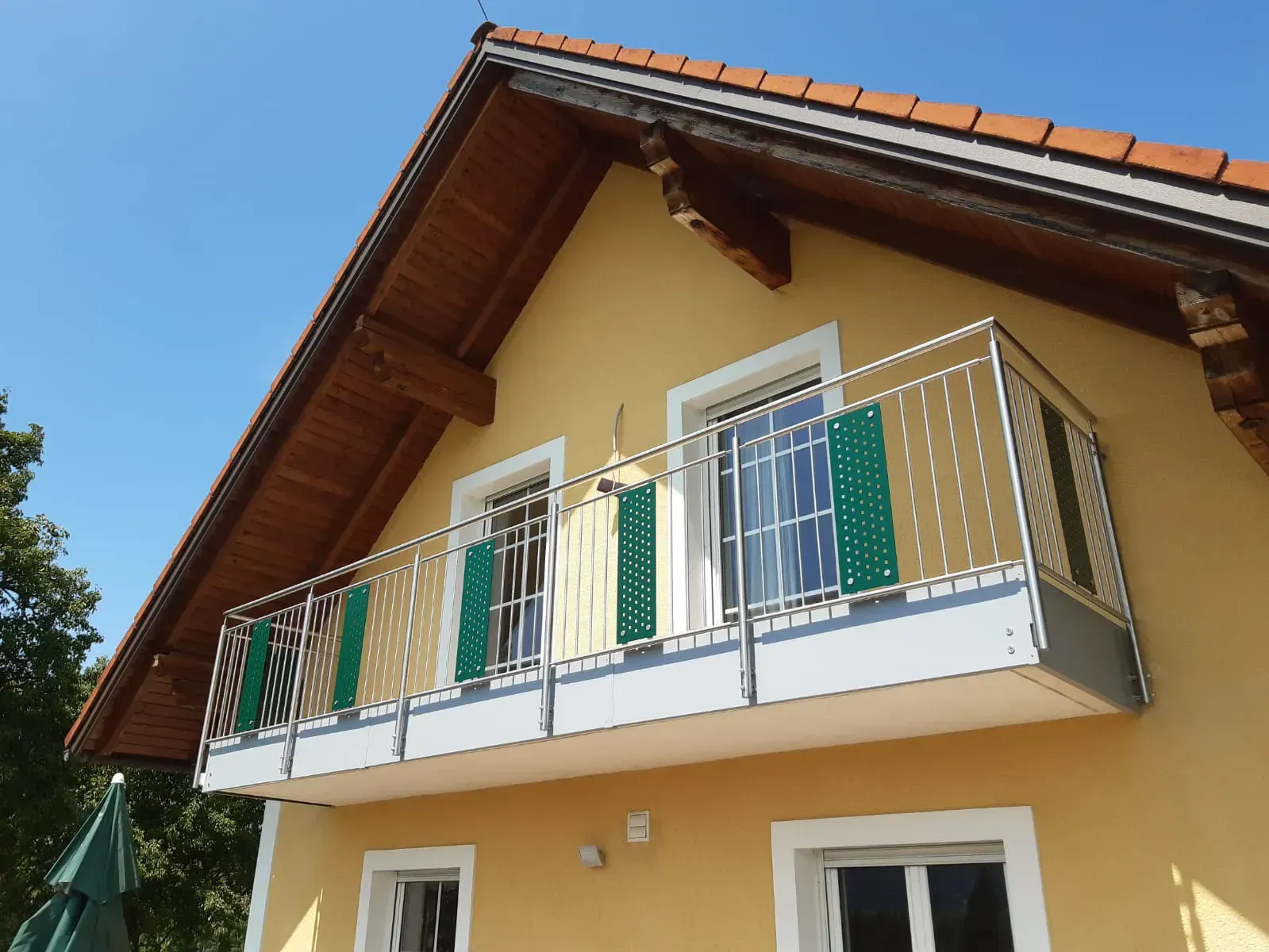 Ein gelbes Haus mit Balkon und grünen Fensterläden