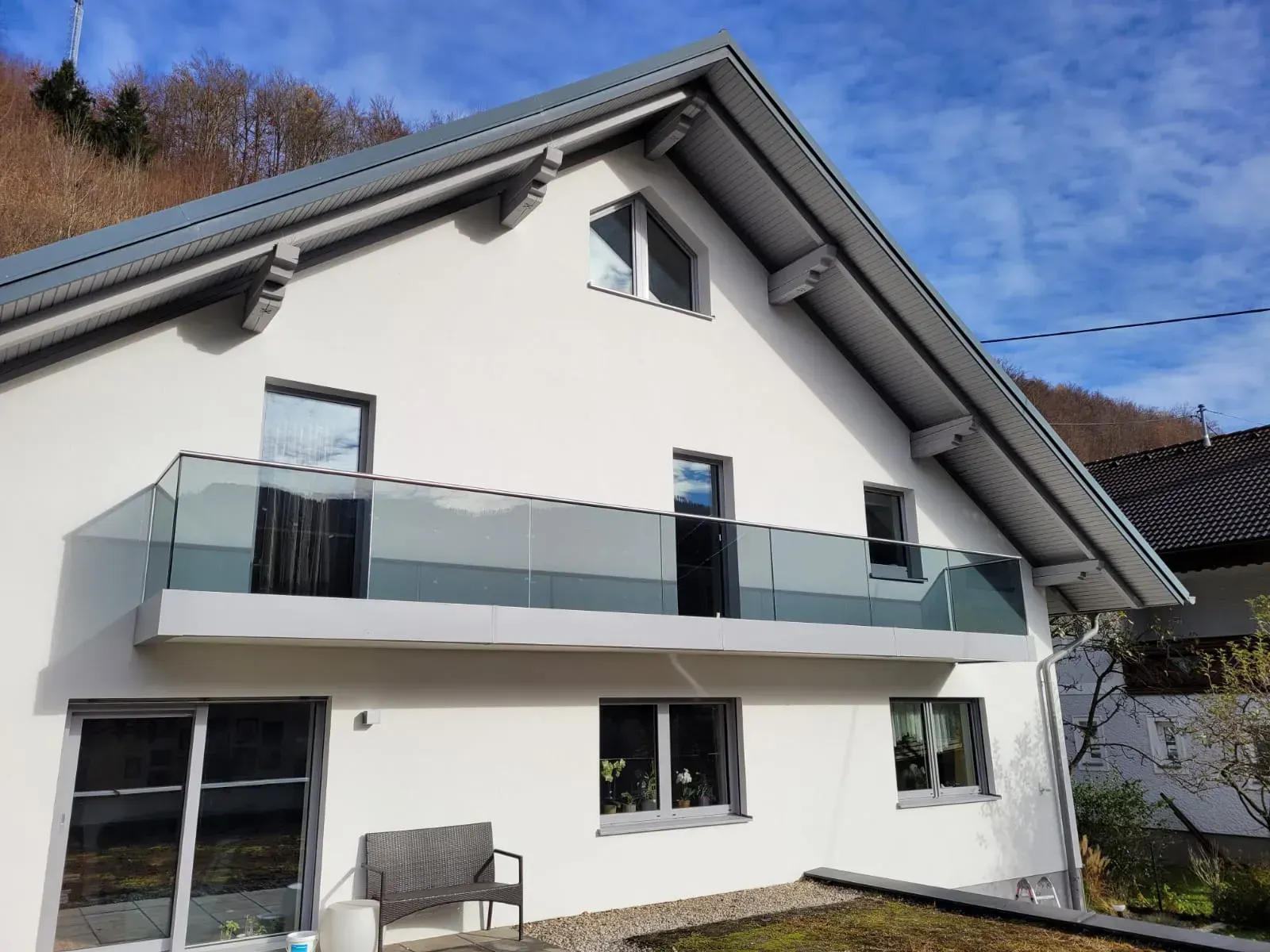 Ein weißes Haus mit einem Balkon und einer Bank davor