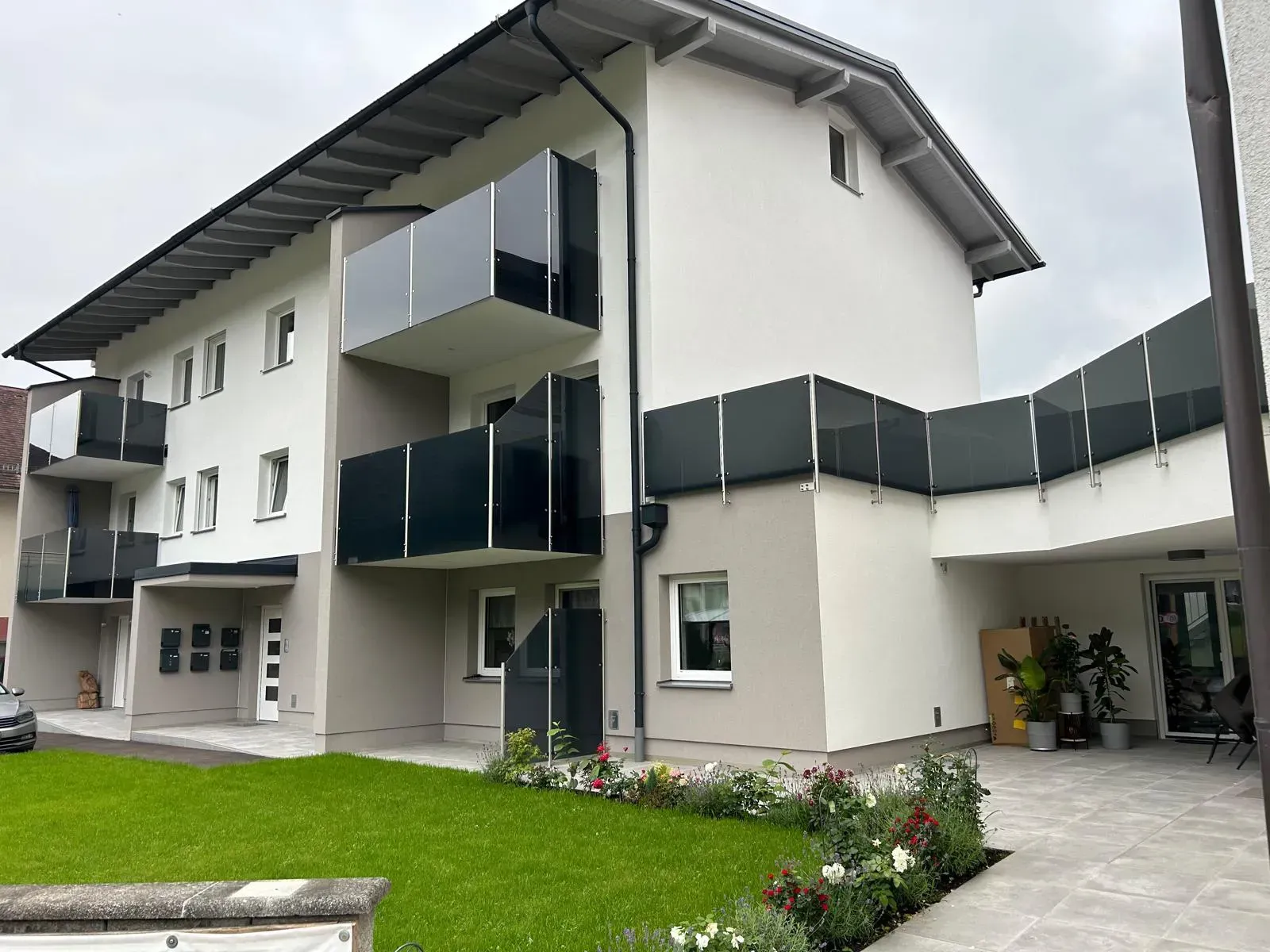 Ein großes weißes Gebäude mit Balkonen und einer Wiese davor.