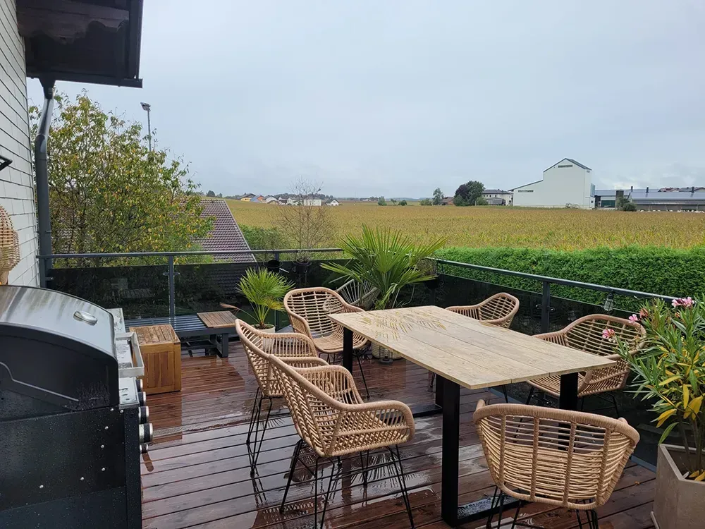 Auf der Terrasse mit Aussicht auf ein Feld gibt es einen Tisch und Stühle.