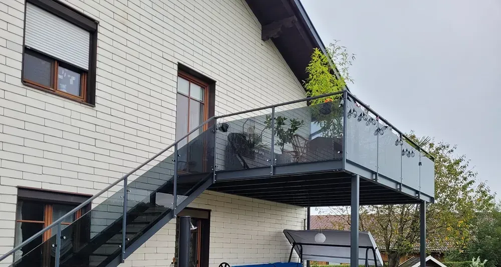 Ein Haus mit einem Balkon und einer Treppe, die dorthin führt.