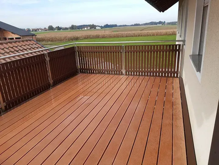 Eine Holzterrasse mit Zaun und Blick auf ein Feld