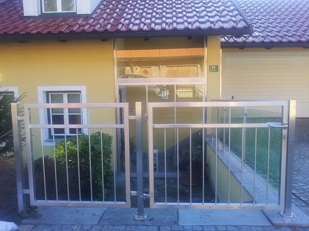 Ein gelbes Haus mit einem Edelstahltor davor
