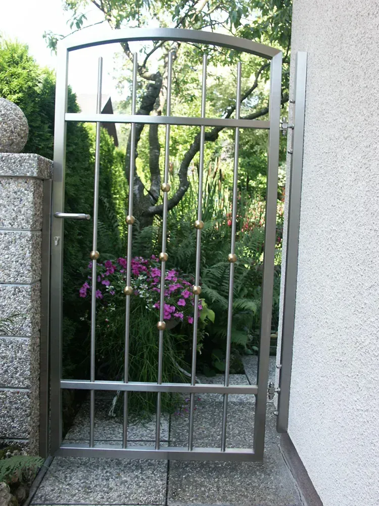 Ein Edelstahltor mit lila Blumen dahinter