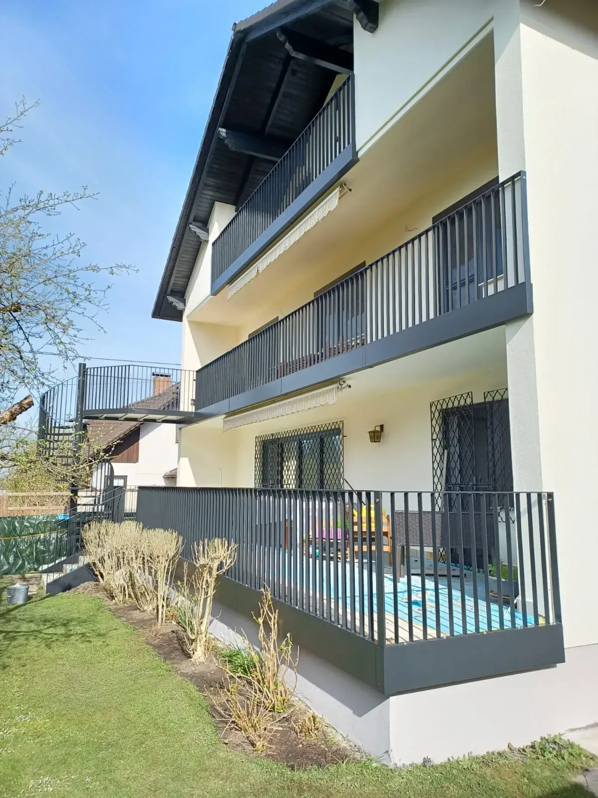 Ein weißes Haus mit einem Balkon und einem schwarzen Geländer