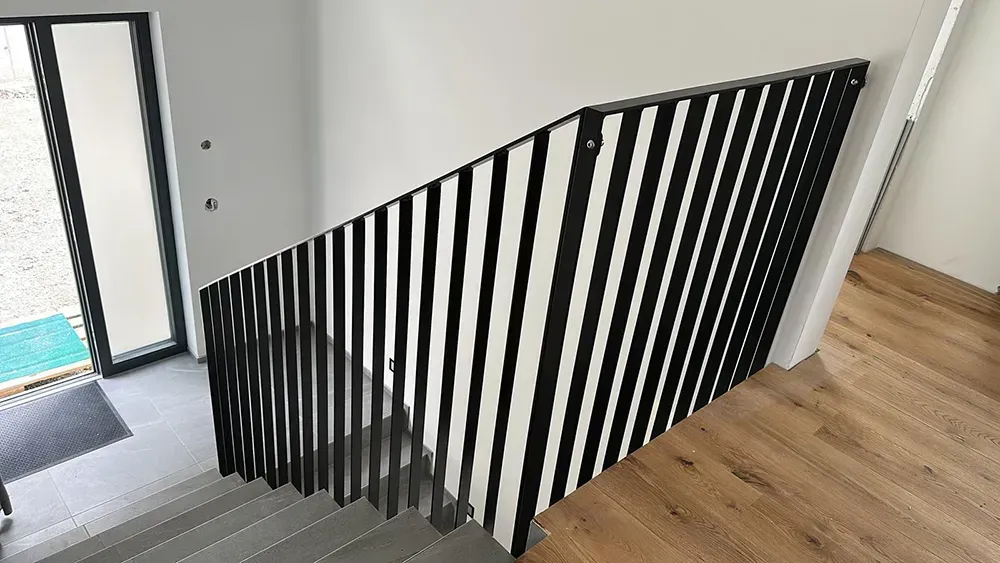 Ein schwarz-weiß gestreiftes Geländer an einer Treppe in einem Haus.
