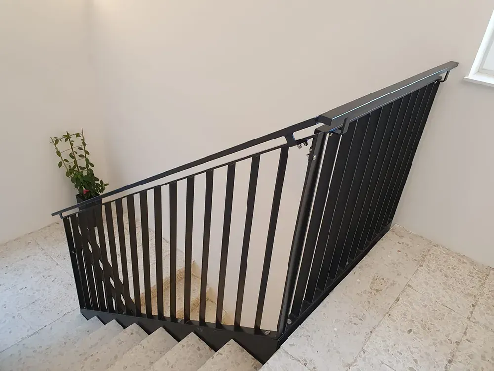 Eine Treppe mit schwarzem Geländer und einer Pflanze in der Ecke.