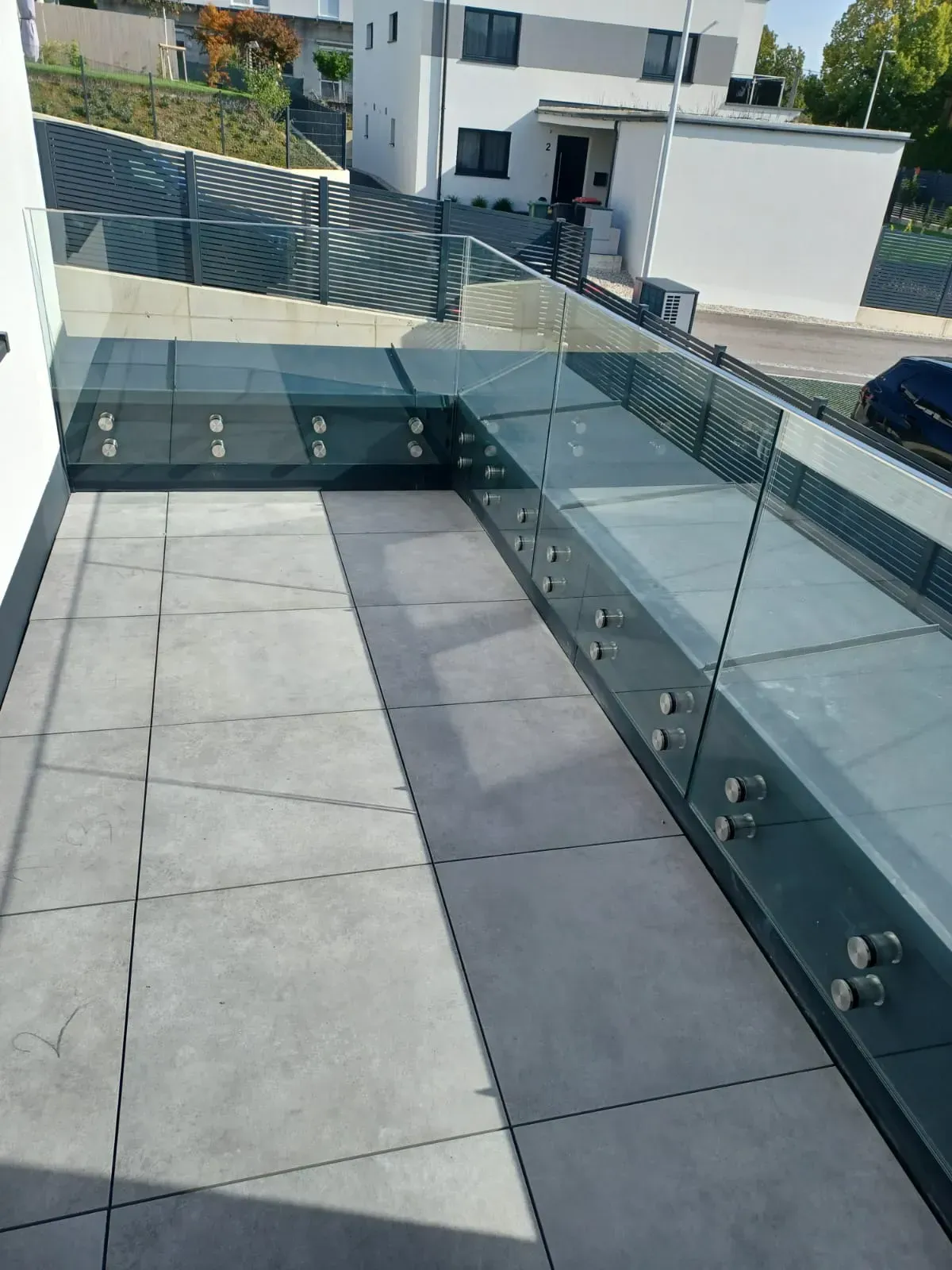 Ein Balkon mit Glasgeländer und Betonboden