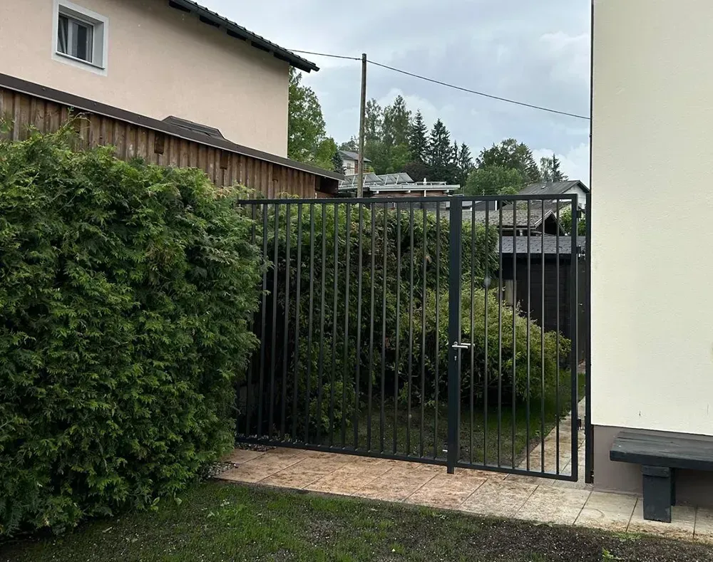 Ein weißes Haus mit einem schwarzen Zaun davor