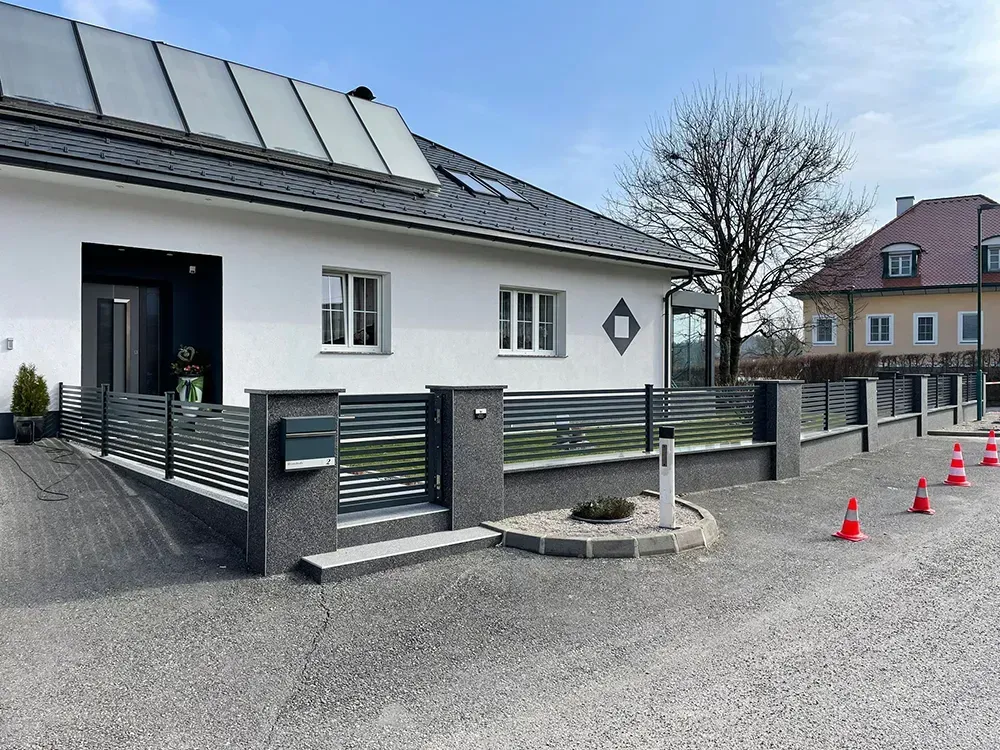 Ein weißes Haus mit einem Zaun und einem Briefkasten davor