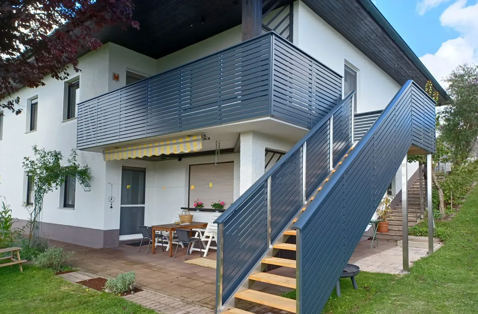 Ein weißes Haus mit einem Balkon und einer Treppe, die dorthin führt.