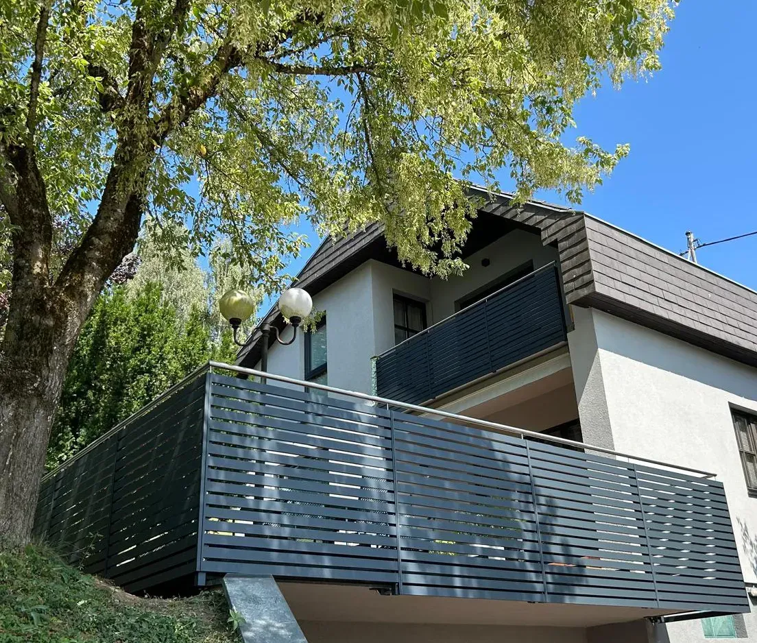 Ein Haus mit einem Balkon und einem Baum davor