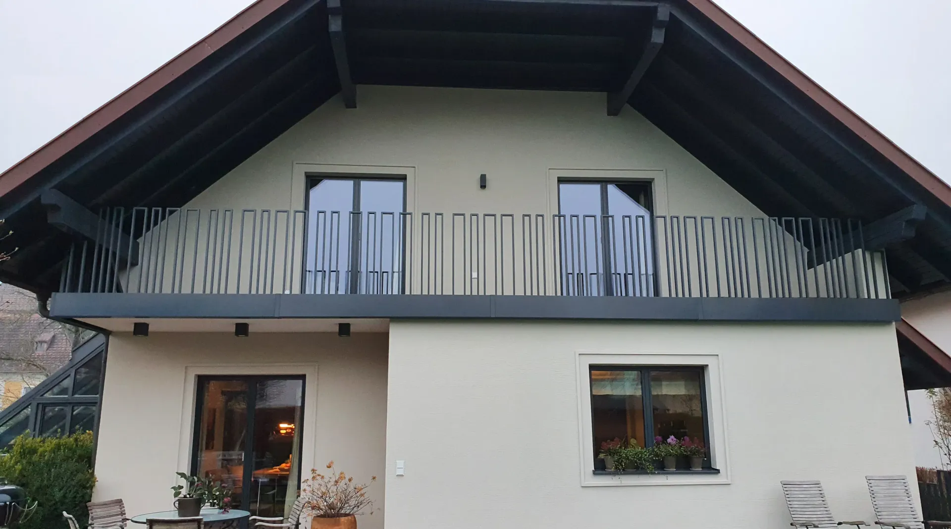 Ein weißes Haus mit einem Balkon oben drauf.