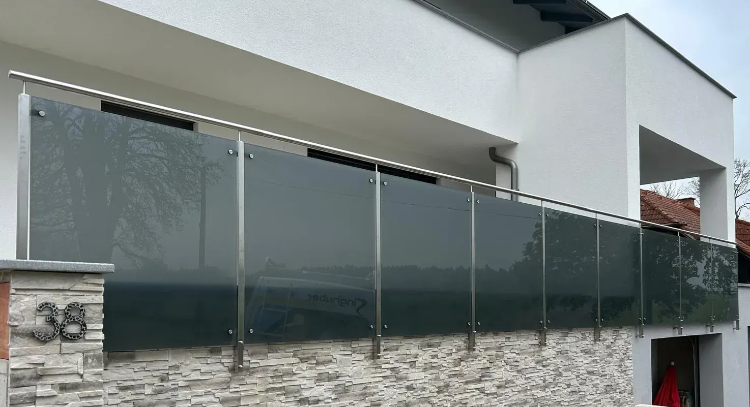 Ein Haus mit einem Edelstahlgeländer und einem Glaszaun.