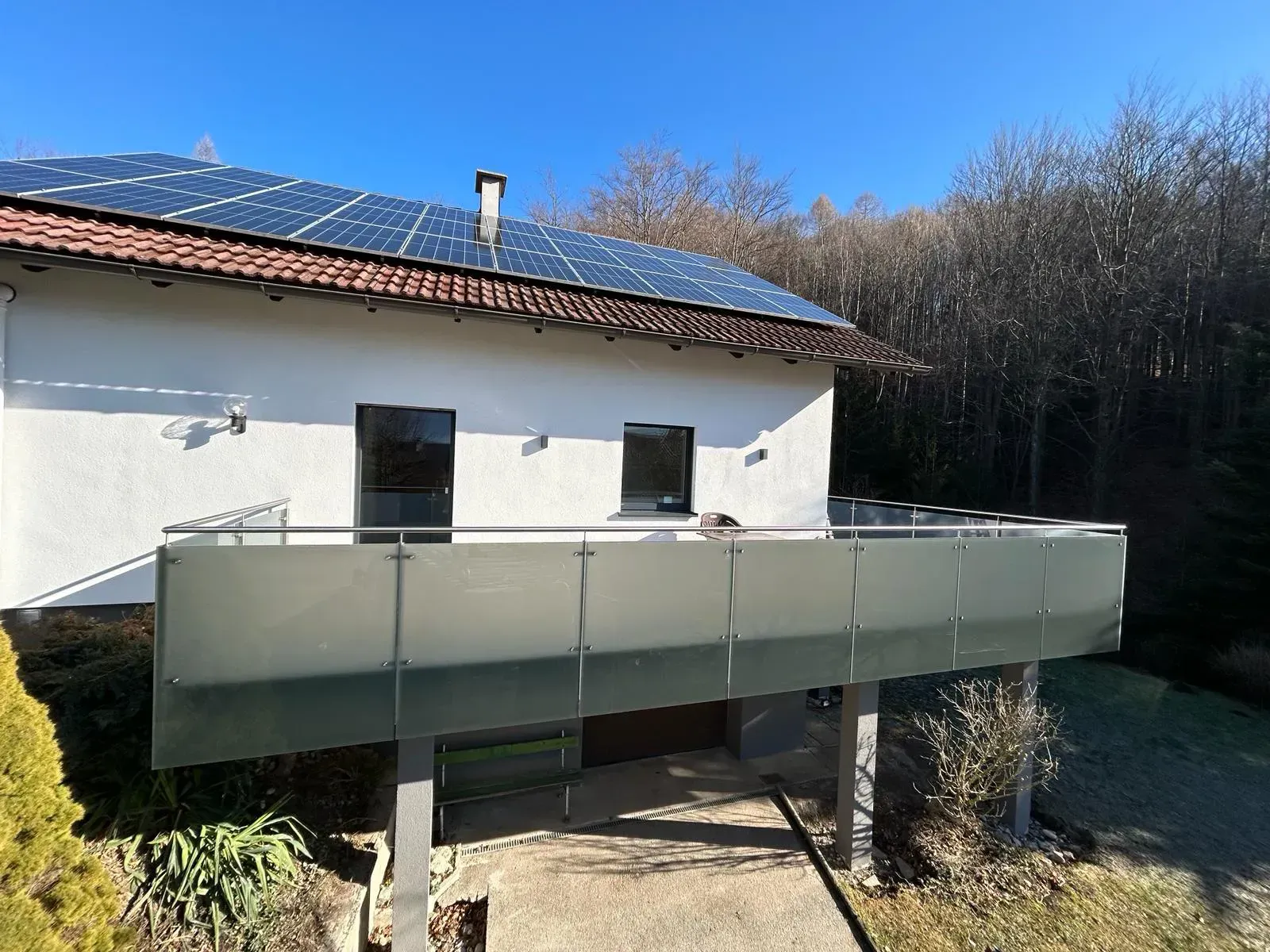 Ein weißes Haus mit Balkon und Sonnenkollektoren auf dem Dach.
