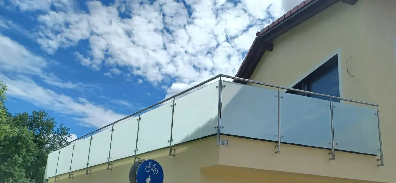 Ein Balkon mit einem Glasgeländer an der Seite eines Hauses.