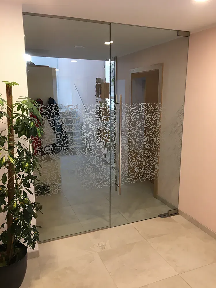 Eine Glastür mit einer Pflanze davor in einem Zimmer.